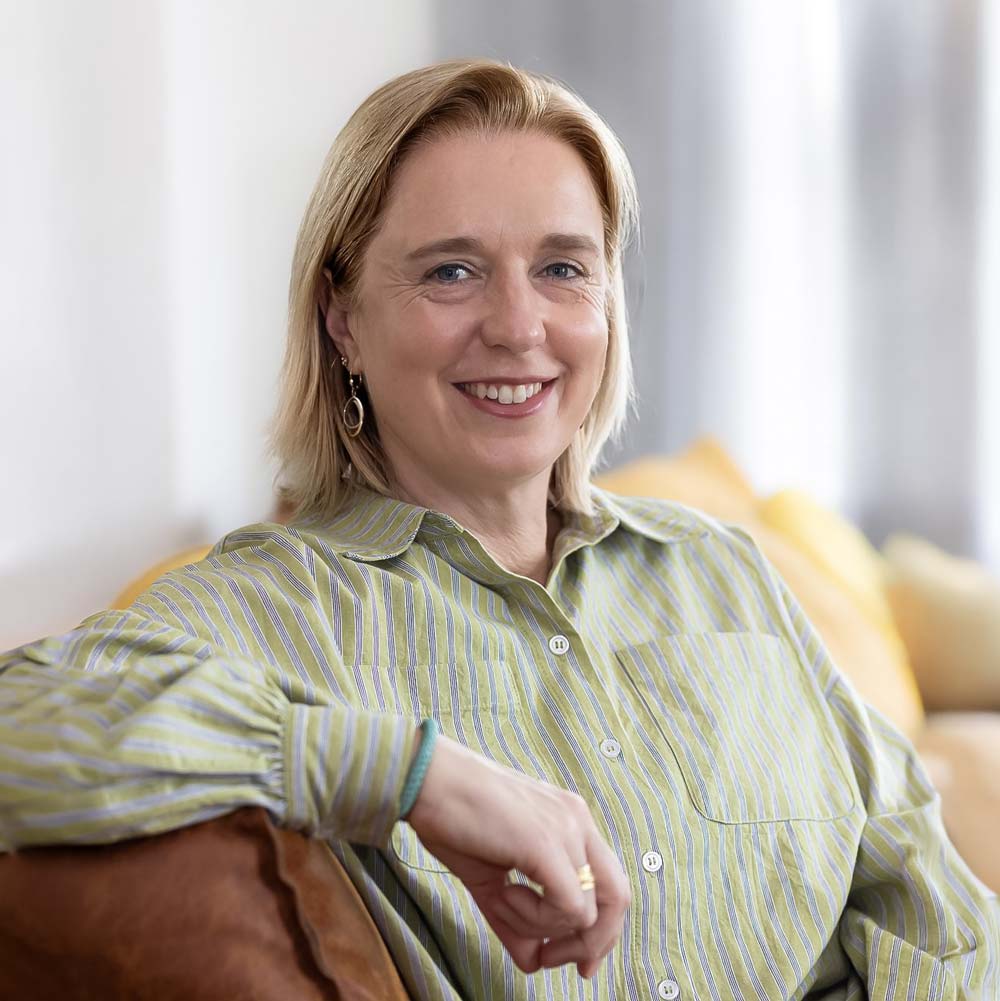 Porträt von Katja Baumann, Bürgermeisterkandidatin in Uplengen, lächelnd auf einem Sofa sitzend