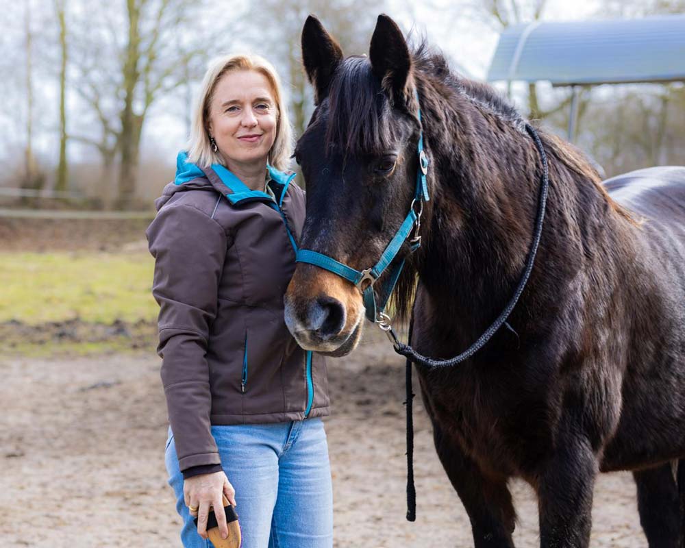 Katja Baumann, Bürgermeisterkandidatin in Uplengen, mit einem Pferd auf einem Reitplatz